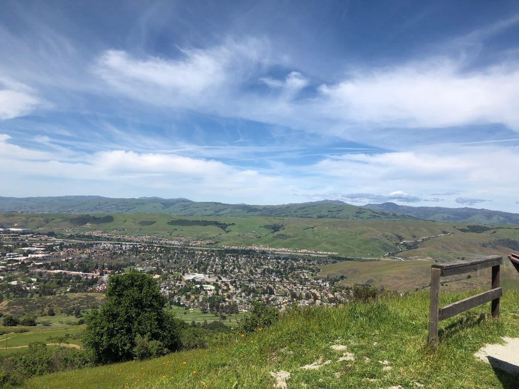 The view from Coyote Peak of south San Jose, an expansive vista of rolling green hills, a bright blue sky, a valley filled with thousands of suburban homes.