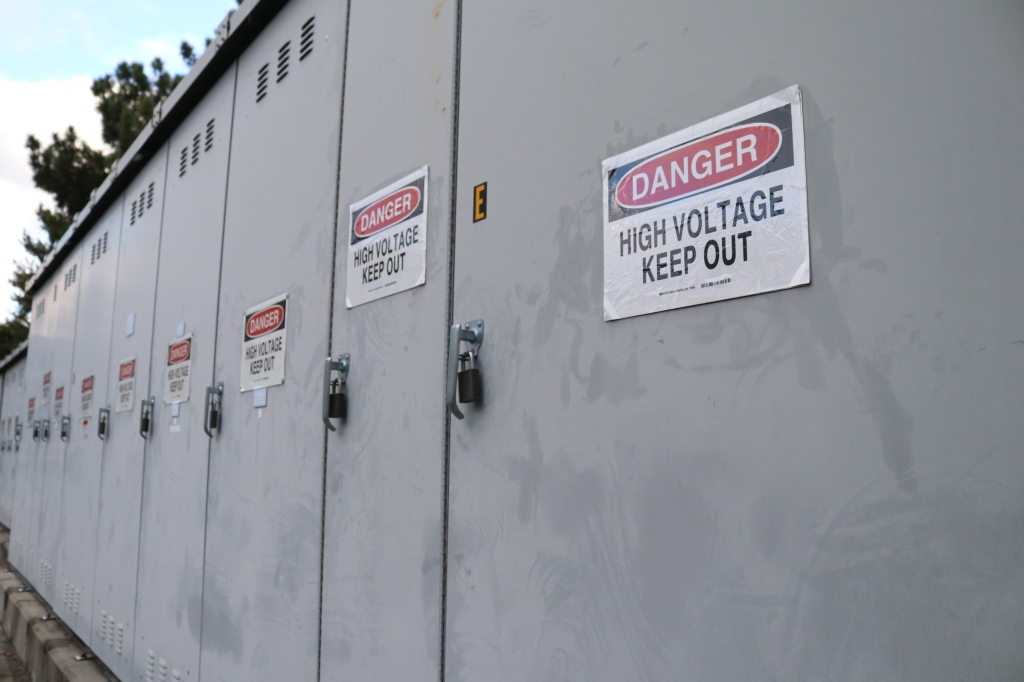 A series of metal lockers each have a "Danger, keep out, high voltage." sign on them. 