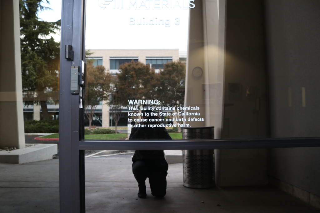 A white decal sits next to the entrance of the building, it reads, "Warning: this facility contains chemicals known to the state of California to cause cancer and birth defects or other reproductive harm." 